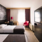 Hotel bedroom with two single beds, feature wall with black and white scene and wall mounted television