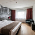 Hotel bedroom with large double bed, feature wall with balck and grey city scene and wall mounted television