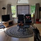 Living room with pine flooring and round blue and white patterned mat with black round coffe table in the middle
