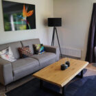 Living room with grey two seater sofa and pine coffee table on dark grey mat