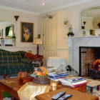 Classic living room featuring a marble fireplace with a roaring fire, a green plaid sofa, and a large mirror reflecting the room's decor.