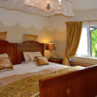 Traditional luxury holiday accommodation bedroom with ornate wooden furniture and a classic chandelier.