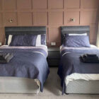 Bed room with double and a single bed against a brown painted panel wall