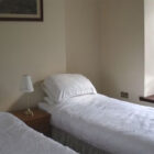 Two single beds next to a window with bedside cabinet between