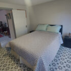 Double bed in bedroom with decorative geometric floor tiles.