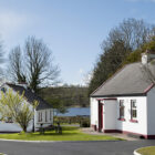 Two white painted cottages with tiled sloping roof and views across a lake