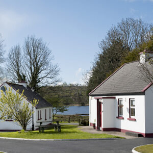 Two white painted cottages with tiled sloping roof and views across a lake
