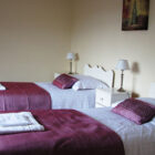 Bedroom with two single beds with white linen, purple thows and cushions