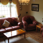 Living room with burgandy leather sofa and chairs around a pine coffee table