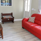 Living room with red leather sofa and small wooden table with flowers in a white vase