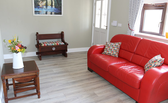 Living room with red leather sofa and small wooden table with flowers in a white vase