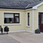 Bungalow with pale lemon painted walls and porch with brown door