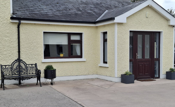 Ireland Fishing Holidays Coaches Corner Castleblayney (3) Bungalow with pale lemon painted walls and porch with brown door