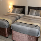 Bedroom with two single beds with grey and brown striped bed linen