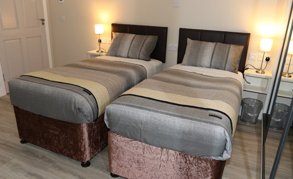 Bedroom with two single beds with grey and brown striped bed linen