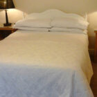 Bedroom with double bed with white linen and two bedside cabinets with table lamps on