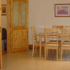 Dining room with light pine table and six chairs with double doors open leading into a living room