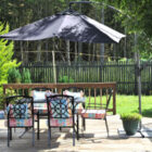 Wooden garden deck with outdoor dining furniture and a large black parasol.