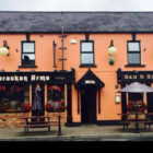 Two storey hotel with peach painted walls and black framed windows and doors