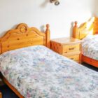 Two single pine beds with pine bedside cabinets and patterned bed linen