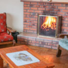 Open fire in a brick fireplace with armchairs at either side