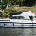White cruiser moored against a river bank