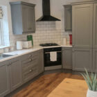 Modern kitchen with slate grey shaker-style cabinets, white quartz countertops, and a white subway tile backsplash.