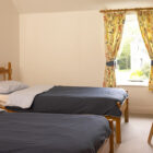 Bedroom with two single beds either side a bedside cabinet with red table lamp on it