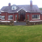 Red single storey building with grey slate roof and stone wall to the front