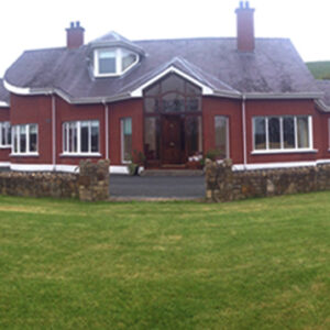 Red single storey building with grey slate roof and stone wall to the front