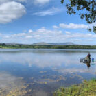 Angler sat on a stand at the edge of a lake fishing