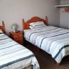 Bedroom with two single beds with pine head boards and pine bedside cabinet between them