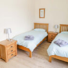 Two pine single beds with pale blue linen and pine bedside cabinets