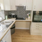 Kitchen with cream units and grey tiles