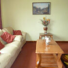 Lounge with white leather settee and pink cushions and candle on a pine coffee table