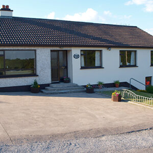 Cream painted bungalow with steps leading to the front door and steps leading down a bank to a lower level