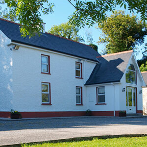 Large two storey house painted white with double storey porch to one side with large windows