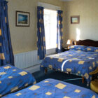Large bedroom with double and two single beds with blue and yellow patterned bed linen