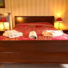Bedroom with double bed with red and gold patterned bed linen