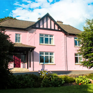 Large two storey farmhouse painted pink with garden to the front