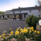 Drive leading past daffodil flower bed up to a two storey house