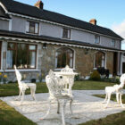 White wrought iron patio furniture on a paved area infront of house with daffodils growing in the garden