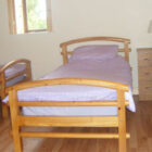Bedroom with two single pine beds with lilac linen