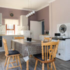 Kitchen with white range cooker and pine dining table with plastic table cloth and four pine dining chairs