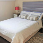 Bedroom with double bed with a striped headboard, two bedside cabinets with lamps