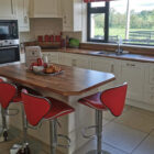 Cream kitchen with wood counter tops and kitchen island with four red stools