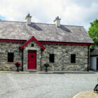 Stone built cottage with grey slate roof and red painted door