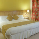 Hotel bedroom with large double bed and two lamps lit on bedside cabinets either side of the bed