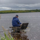 Angler sat on a fishing stand on a river