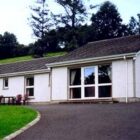Single storey white bungalow with lawn and drive to the front